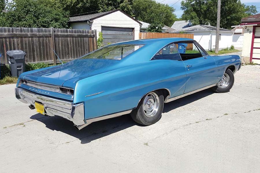 Image showing metallic blue 1967 Pontiac Parisienne two-door hardtop parked behind a garage.