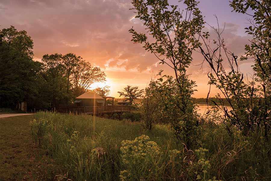 Image showing a small wooden cabin beside a lake at sunset.