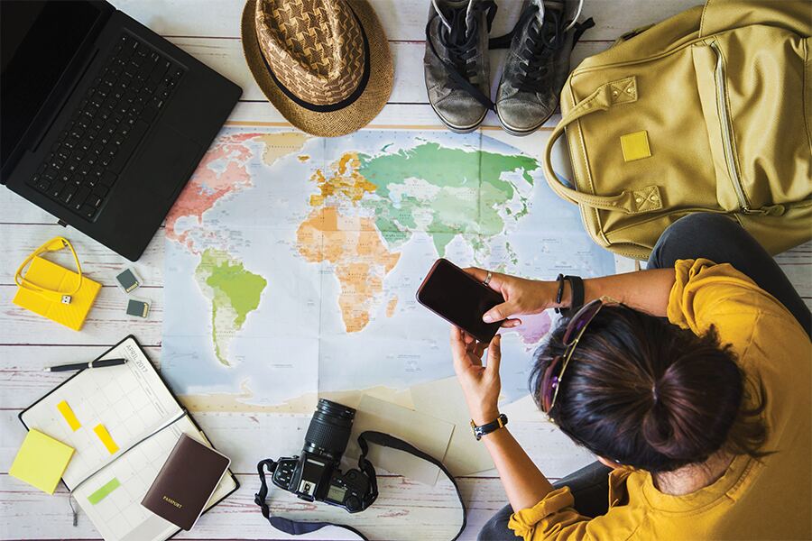 image showing an overhead view of a man with a map spread on the floor and various pieces of hiking equipment around him.