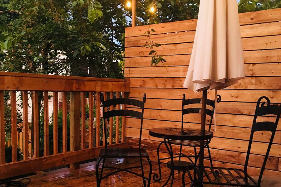 Image showing a wooden deck with patio table, umbrella and deck chairs.