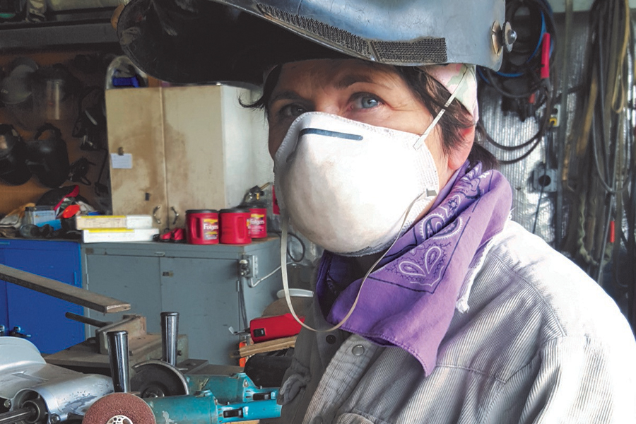 Image showing a woman wearing a dust mask and a welder's helmet in a workshop.