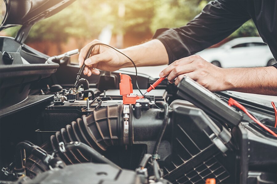 Image showing the closeup of a car engine with two hands holding electronic diagnosting tools.