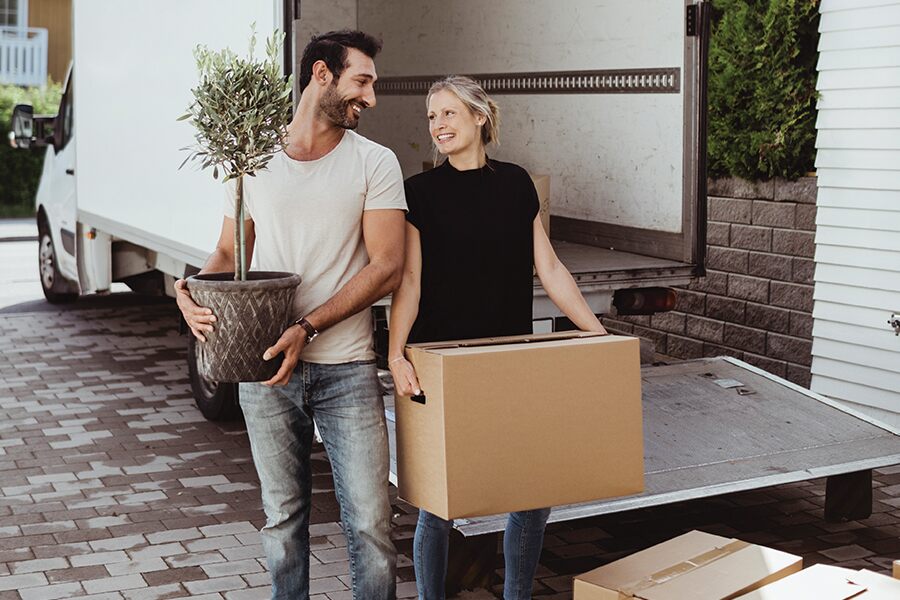 Image of a young couple unloading furniture from a small truck.