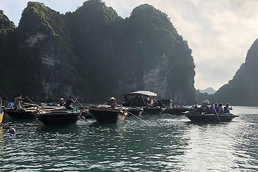 Image showing a group of sampans floating on a river in Cambodia with rocky outcroppings in the background.