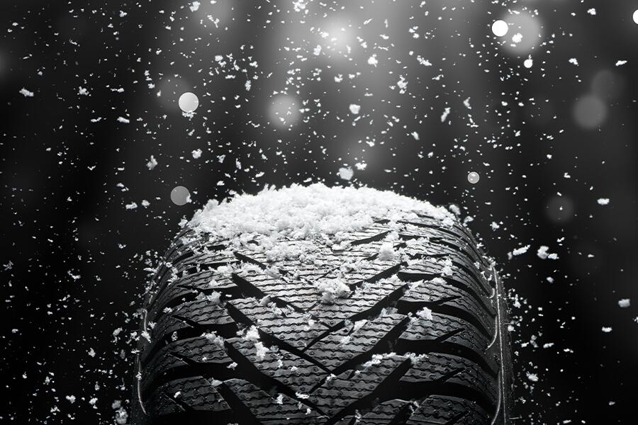 Image showing a closeup of a winter tire with snowflakes falling on the top of the tire.