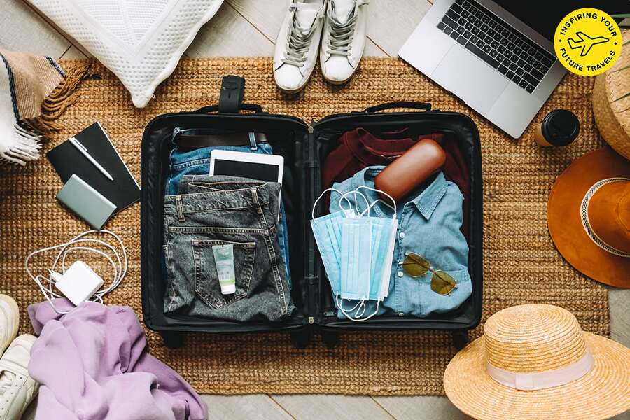 Image showing an open suitcase with various articles of clothing and travel accessories waiting to be packed.