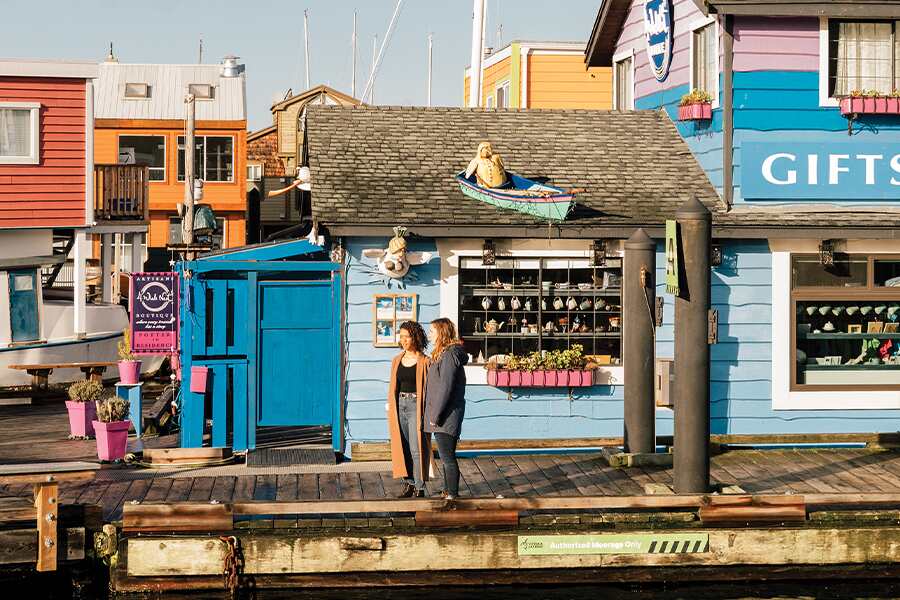 Image showing two women standing on a dock among colourful buildings on Fisherman's Wharf in Victoria, British Columbia.