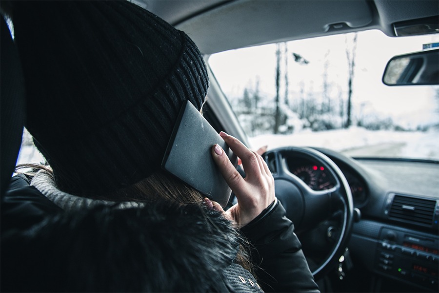 Image showing a young driver behind the wheel while talking on a cellphone.