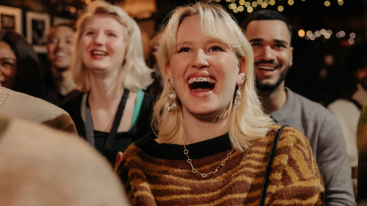 A woman sitting in a theatre laughing