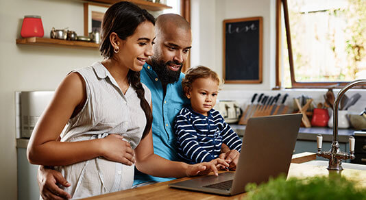 Family looking at laptop in kitchen.