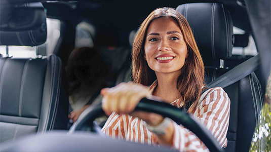 A woman sitting inside a vehicle looking out front.