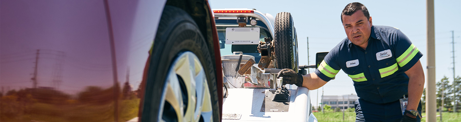 Tow truck driver checking the safety of attached car spring.