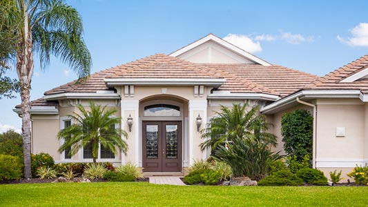 A large bungalow house surrounded by palm trees during the day.