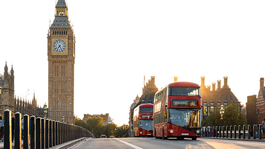 Red buses crossing Westminster Bridge near Big Ben.