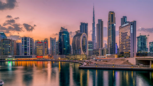 The Dubai waterfront skyline glowing at sunset.