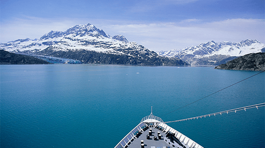 Cruise ship bow facing snow-covered mountains.