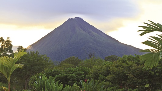 View of lush green Costa Rican jungle with blue-grey mountain in background.