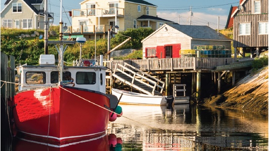 A red boat docked at a port with houses in the background.