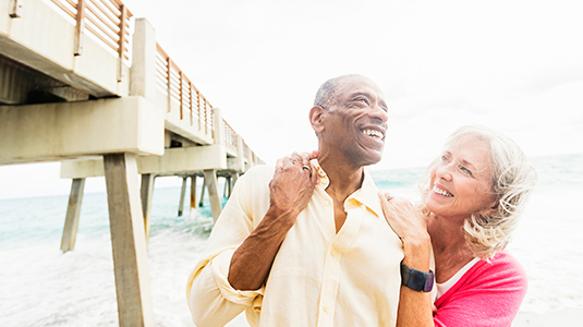 Older couple walking under boardwalk on beach