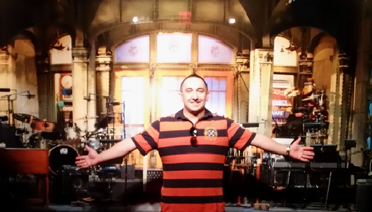 Image showing CAA travel consultant Kyle Kneller smiling with outstretched arms against restaurant background.