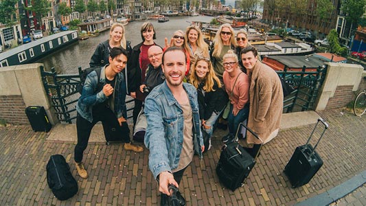 A group of travellers taking a group photo with a selfie stick.