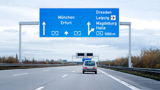 A blue overhead traffic sign along a highway.