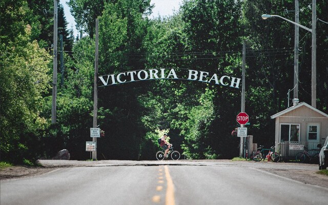 Image showing a road leading into the woods with a sign arch reading Victoria Beach.
