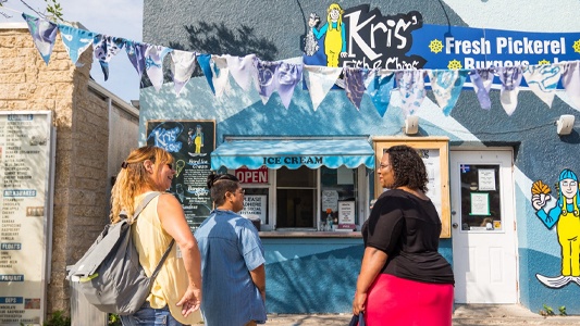 Image showing several people standing outside a small building with the sign Kris's Fish and Chips.