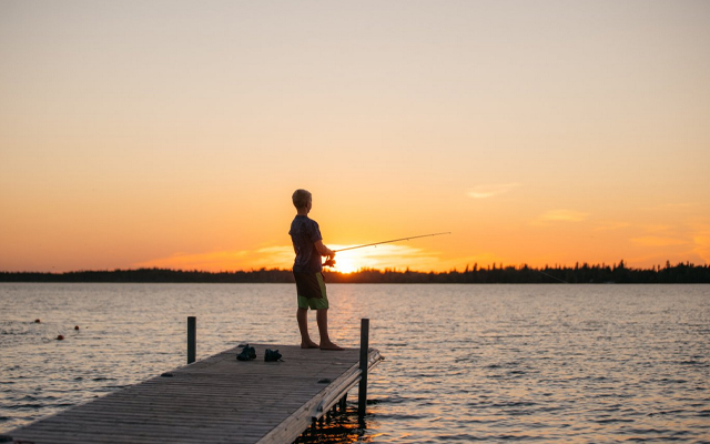 Image showing a man fishing off a dock as the sun sets.