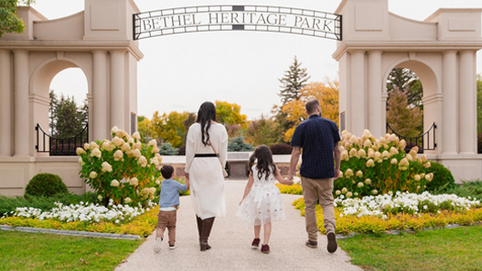 Image showing a young couple with two children walking toward a stane arch and gateway.