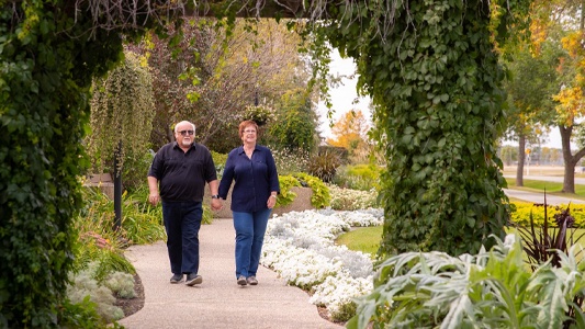 Image showing two people walking down a path toward an arch of ivy vines.