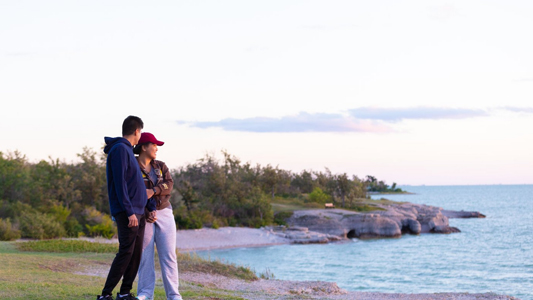 Image showing a young couple standing by a lake and looking out to the distance.