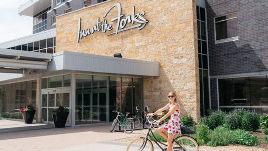 Image showing a teenage girl on a bicycle in front of a haotel entrance.