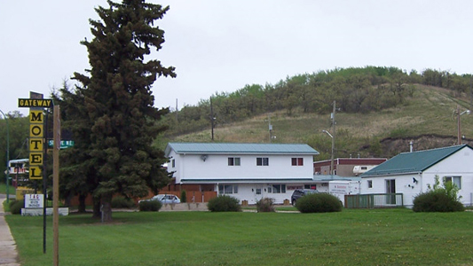 Images showing a large tree, a white and brown hotel structure and outbuildings.