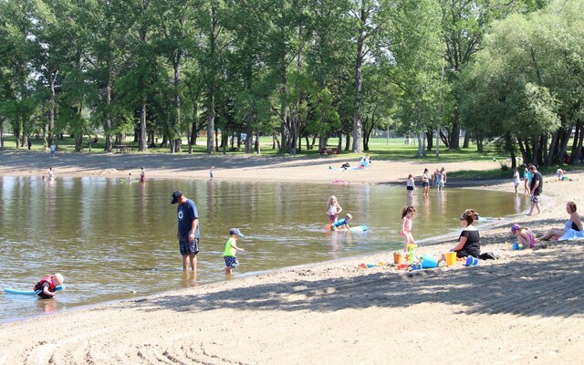 Image of a group of adults and children sunbathing or swimming in a lake.