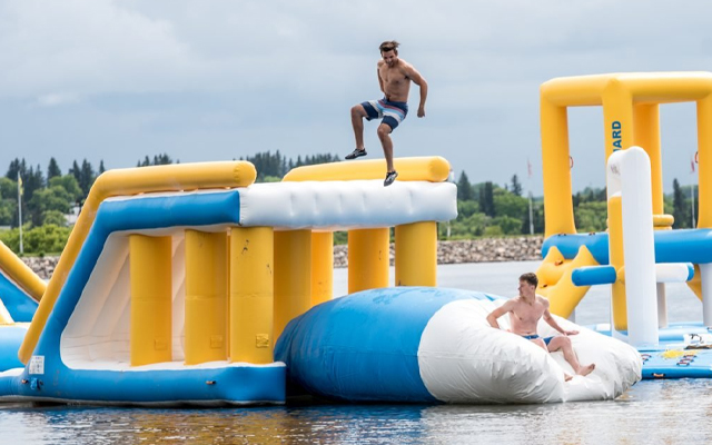 Image showing two young men playing on a large inflatable floating structure.