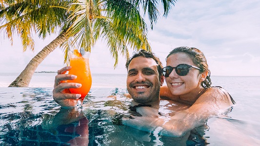 Couple in pool enjoying a cocktail on WestJet Beach Resort