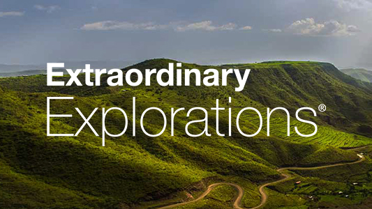 CAA Extraordinary Explorations logo in white lettering with a view of green hills in the background.