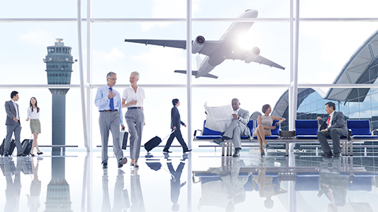 A crowd of people in the airport with a plane taking off in the background.