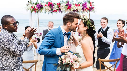 A newlywed couple kissing at a wedding ceremony.