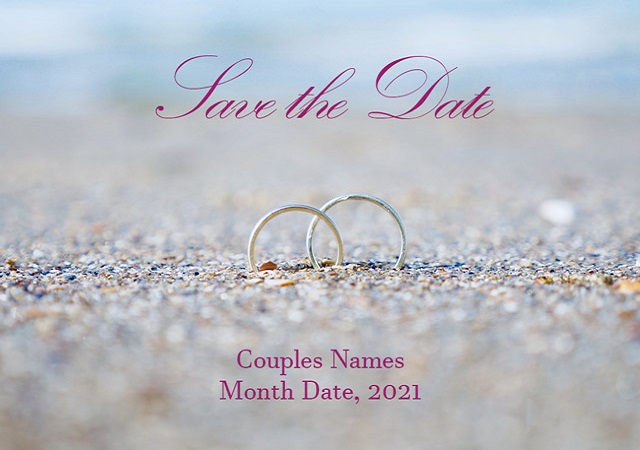 Photo showing eye-level view of two rings embedded in the sand with the words SAVE THE DATE above.