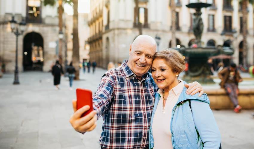 Senior couple taking a selfie in front a fountain in Barcelona