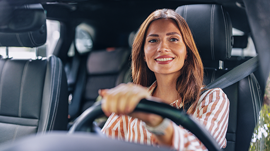 A woman sitting inside a vehicle looking out front.