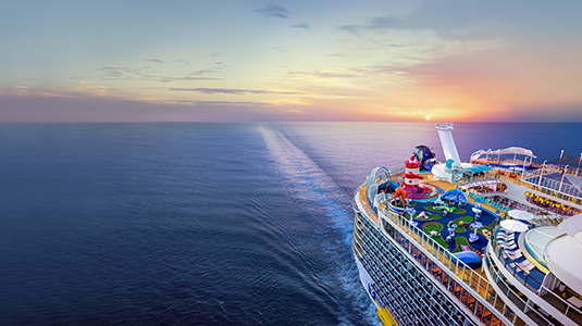 Arial side view of a Royal Caribbean cruise ship sailing an ocean.