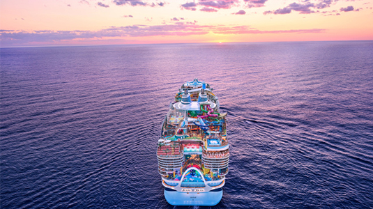 Arial back view of a Royal Caribbean cruise ship sailing an ocean.