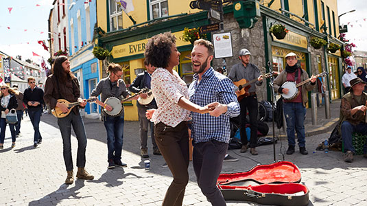 Couple dancing in the street with a band playing music behind them