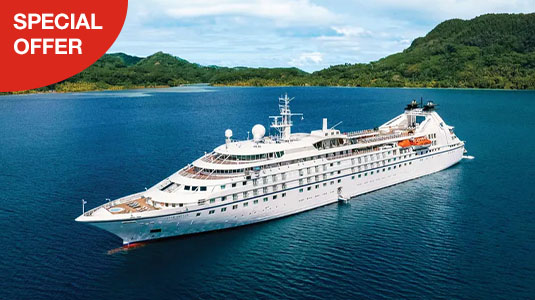 Windstar cruise ship on water passing high green hills. Special offer.
