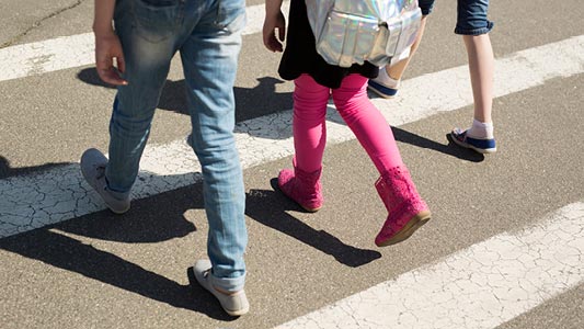 Children crossing a cross-walk going to school.