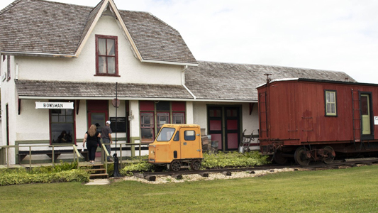 Image showing an old-style train station with a caboose and rail car in front.