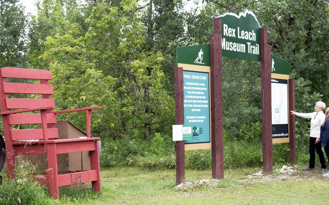 Image showing a large red wooden chair and a sign reading Rex Leach Museum Trail.